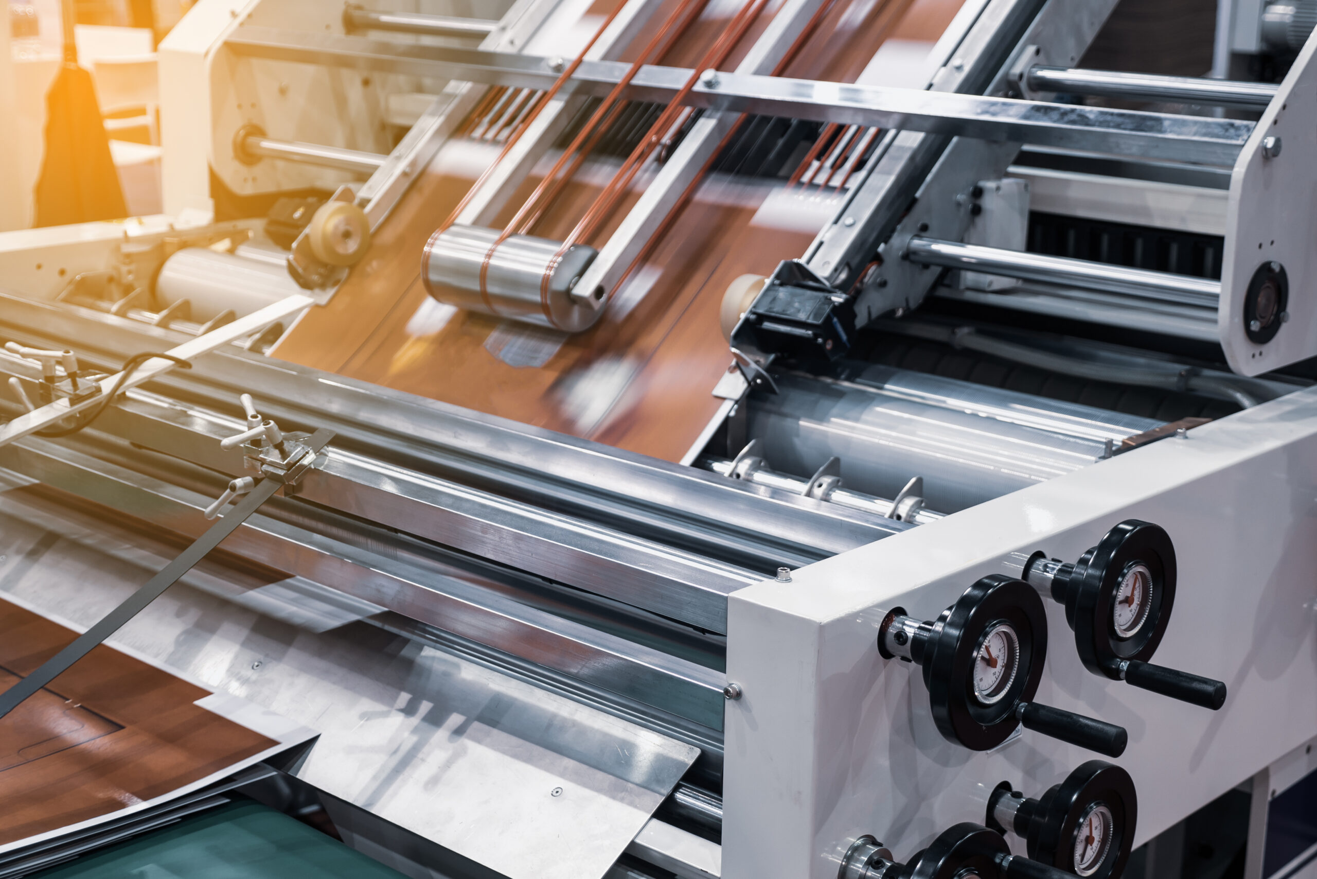 Industrial printing machine with rollers and conveyor system, depicting the process of material handling in a manufacturing setup.